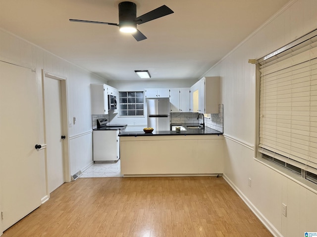 kitchen with sink, stainless steel appliances, decorative backsplash, white cabinets, and light wood-type flooring