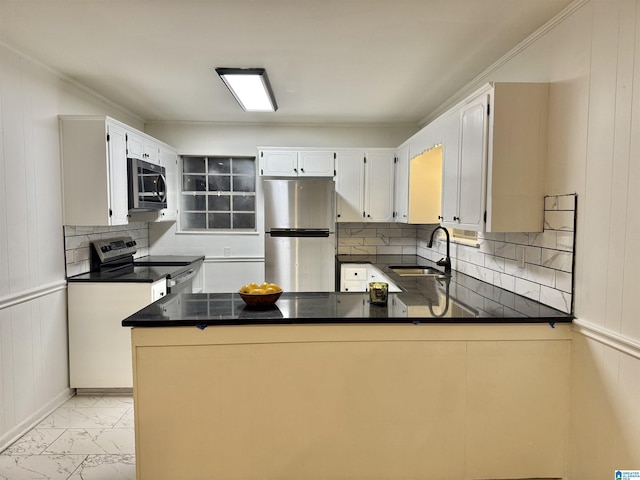 kitchen with white cabinets, wood walls, kitchen peninsula, and appliances with stainless steel finishes