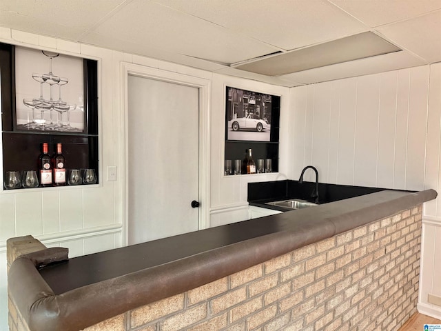 bar featuring hardwood / wood-style floors, built in features, wood walls, and sink