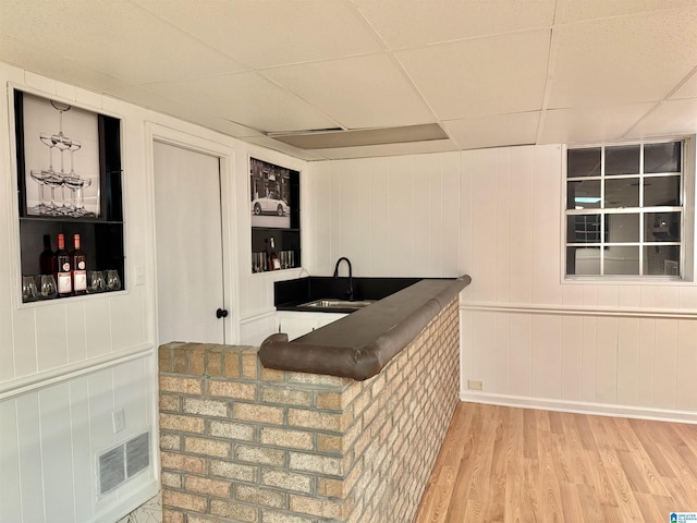 bar featuring wood walls, sink, a drop ceiling, and hardwood / wood-style flooring