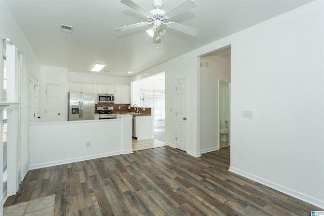 kitchen featuring sink, stainless steel appliances, dark hardwood / wood-style flooring, backsplash, and white cabinets