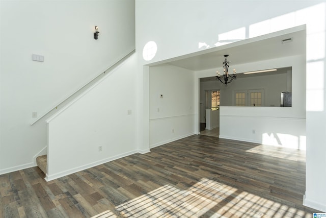 unfurnished living room with dark hardwood / wood-style flooring and an inviting chandelier