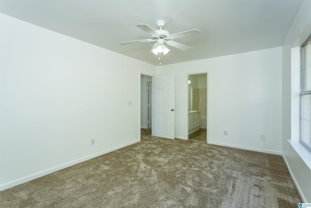 unfurnished bedroom with multiple windows, ceiling fan, ensuite bath, and light colored carpet