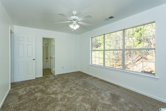 unfurnished room featuring dark carpet, a wealth of natural light, and ceiling fan