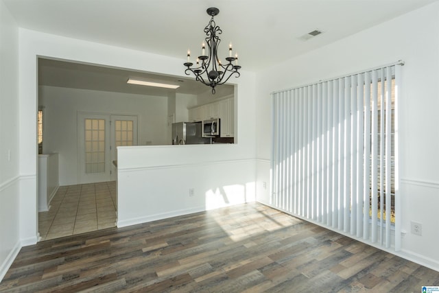 unfurnished dining area featuring a chandelier, french doors, and dark hardwood / wood-style floors