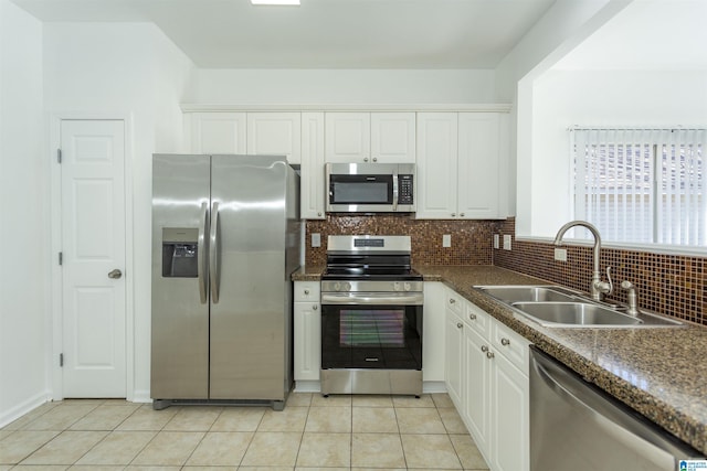 kitchen featuring sink, decorative backsplash, appliances with stainless steel finishes, light tile patterned flooring, and white cabinetry