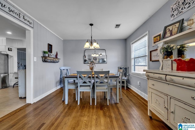 dining space featuring hardwood / wood-style floors, wooden walls, and a notable chandelier