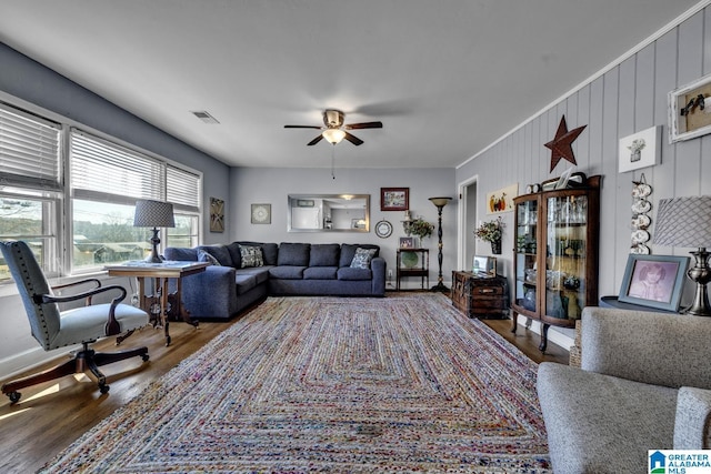 living room featuring ceiling fan, wooden walls, and wood-type flooring