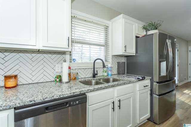 kitchen with sink, light stone countertops, light wood-type flooring, white cabinetry, and stainless steel appliances