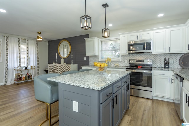 kitchen featuring light wood-type flooring, appliances with stainless steel finishes, a center island, and white cabinetry