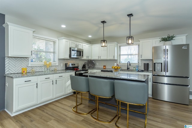 kitchen with decorative backsplash, light stone countertops, light wood-type flooring, and appliances with stainless steel finishes