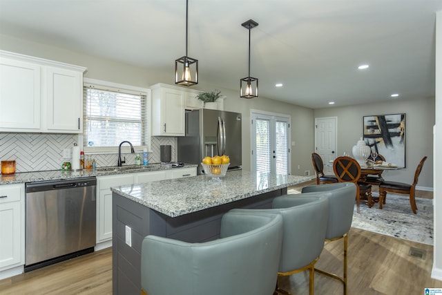 kitchen with white cabinetry, a kitchen island, pendant lighting, and appliances with stainless steel finishes