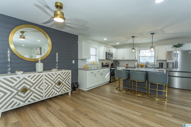 kitchen featuring white cabinets, light stone counters, light wood-type flooring, and appliances with stainless steel finishes