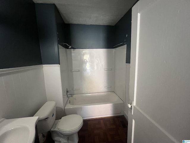 bathroom with parquet flooring, shower / tub combination, a textured ceiling, and toilet