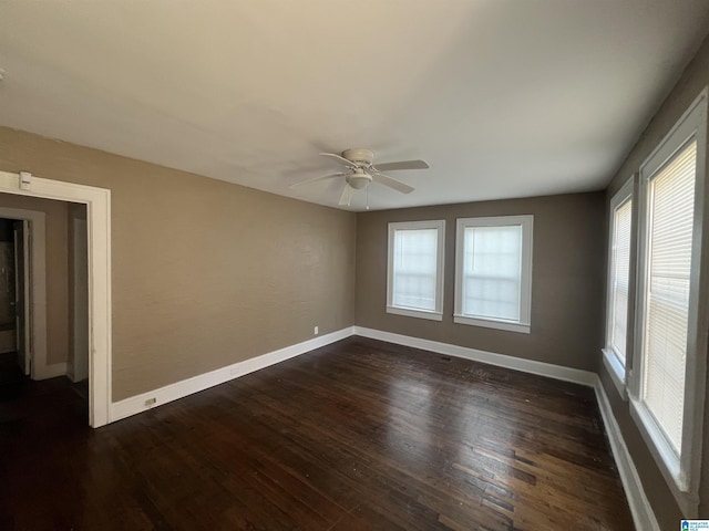 empty room featuring ceiling fan, a healthy amount of sunlight, and dark hardwood / wood-style flooring