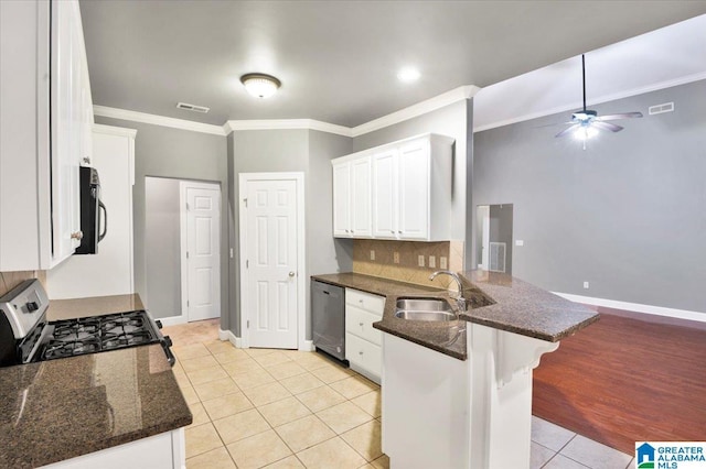 kitchen with a kitchen bar, appliances with stainless steel finishes, kitchen peninsula, light tile patterned floors, and white cabinets