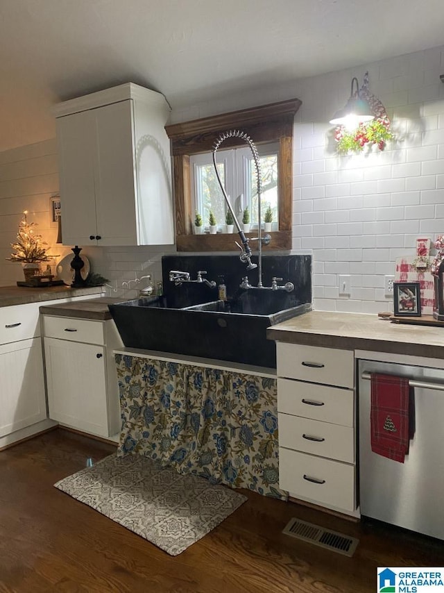 kitchen featuring white cabinets, dark wood-type flooring, stainless steel dishwasher, and tasteful backsplash