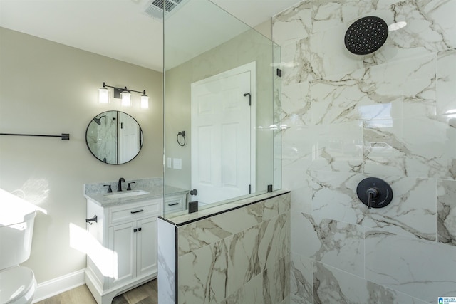 bathroom with vanity, toilet, and a tile shower