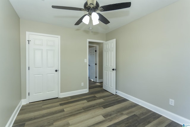 unfurnished bedroom featuring ceiling fan, a closet, and dark wood-type flooring