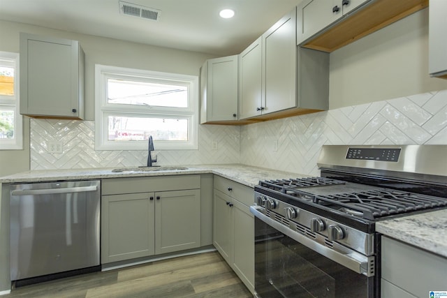 kitchen with a healthy amount of sunlight, sink, light hardwood / wood-style floors, and stainless steel appliances