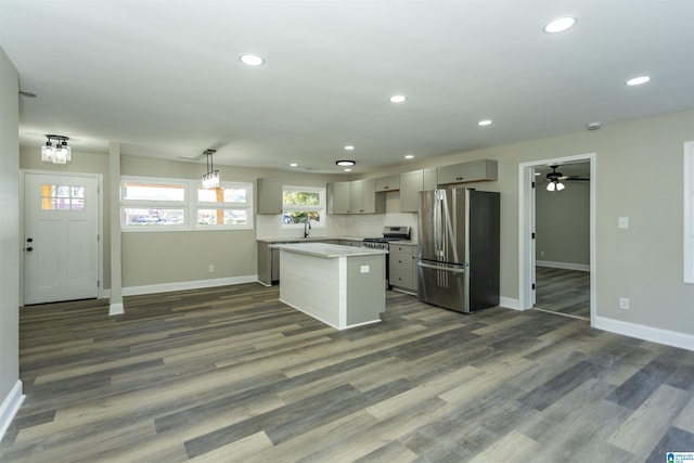 kitchen featuring appliances with stainless steel finishes, pendant lighting, gray cabinets, a kitchen island, and dark hardwood / wood-style floors