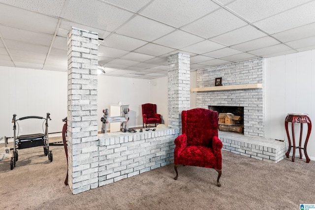 sitting room with carpet flooring, a paneled ceiling, ornate columns, and a brick fireplace