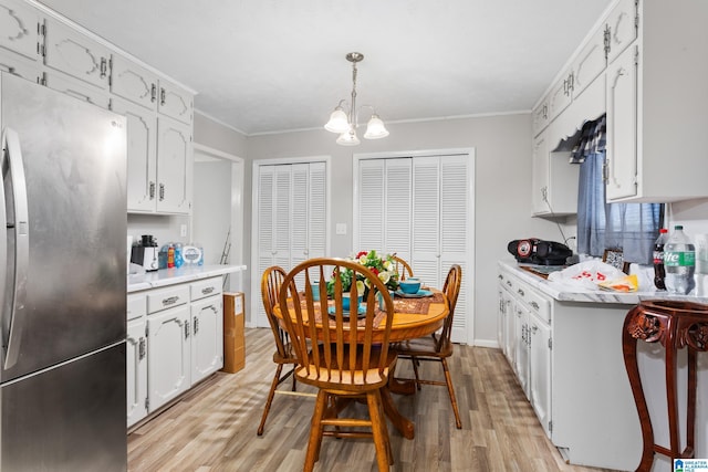 kitchen with decorative light fixtures, light wood-type flooring, white cabinetry, and stainless steel refrigerator