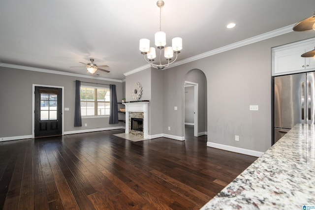 unfurnished living room featuring dark wood-type flooring, ceiling fan with notable chandelier, and ornamental molding