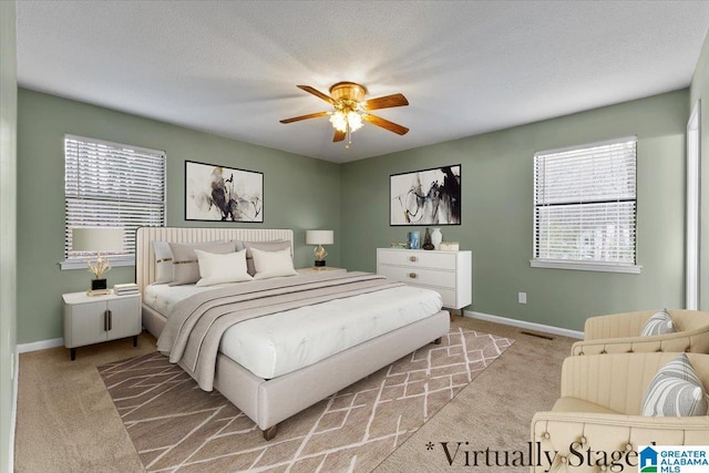 carpeted bedroom featuring ceiling fan and a textured ceiling