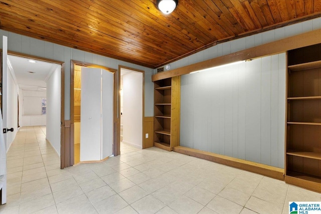 tiled empty room with wooden walls, vaulted ceiling, built in features, and wooden ceiling