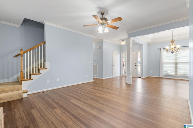 unfurnished living room with wood-type flooring, a tray ceiling, ceiling fan with notable chandelier, ornamental molding, and decorative columns