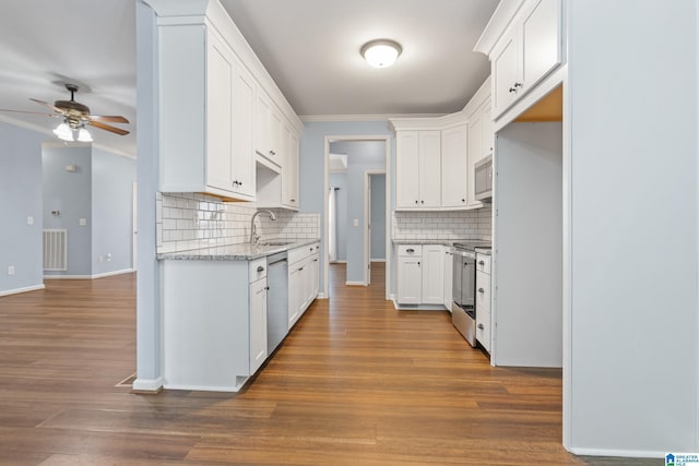 kitchen with white cabinetry, stainless steel appliances, tasteful backsplash, sink, and crown molding