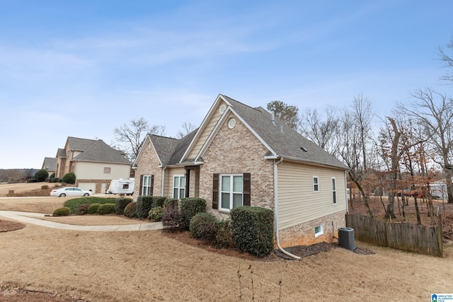 view of front of home featuring central AC unit, roof with shingles, fence, and brick siding