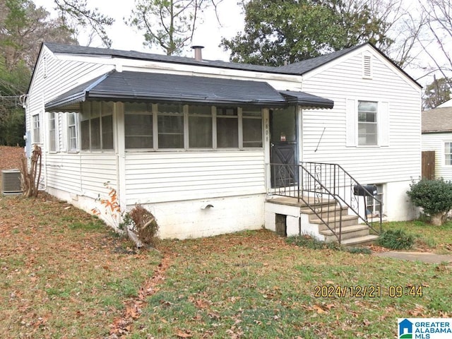 view of front of house with a front yard and central air condition unit