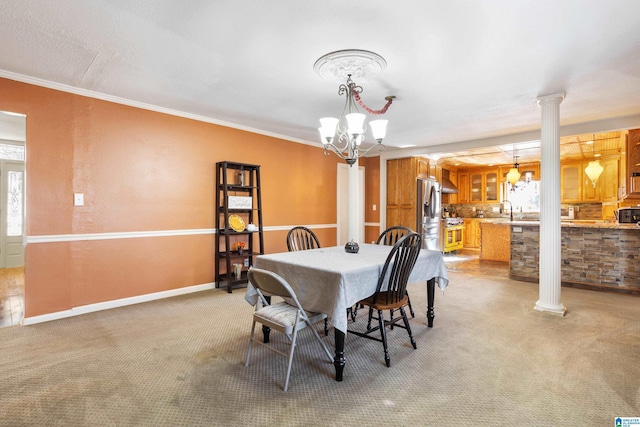 carpeted dining space with decorative columns, crown molding, plenty of natural light, and an inviting chandelier