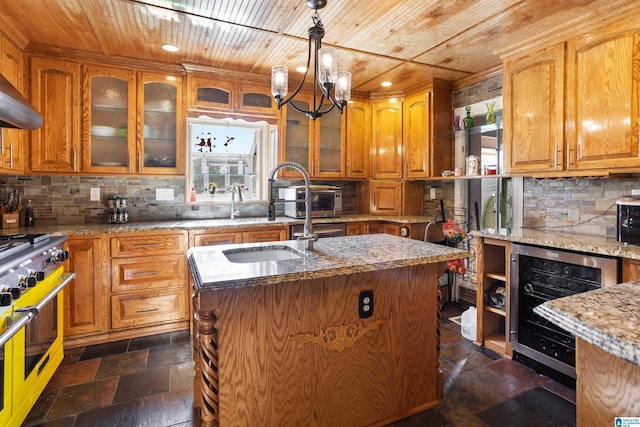 kitchen featuring high end range, wine cooler, a kitchen island with sink, and wood ceiling