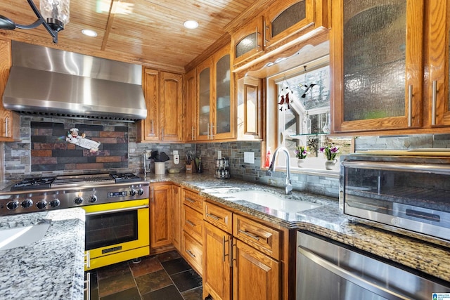 kitchen featuring sink, wall chimney exhaust hood, stainless steel appliances, tasteful backsplash, and light stone counters