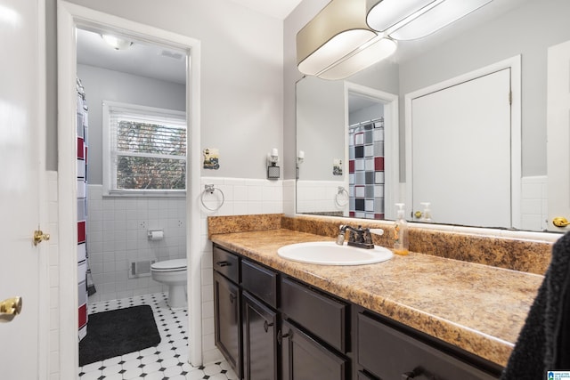 bathroom with vanity, toilet, and tile walls