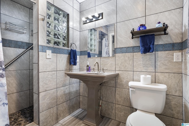 bathroom featuring a shower with curtain, toilet, and tile walls