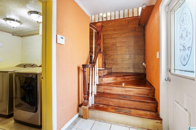 stairway with washing machine and dryer, tile patterned floors, and crown molding