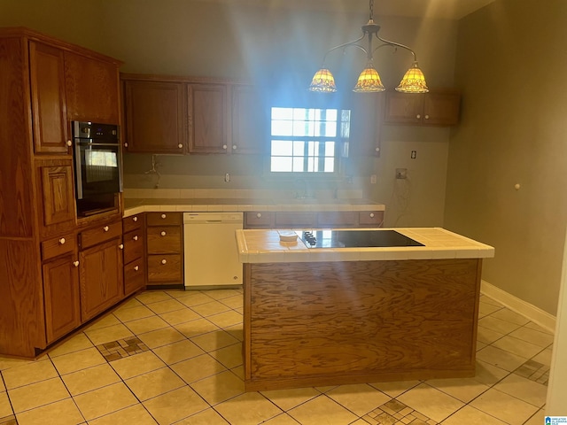 kitchen featuring light tile patterned flooring, tile countertops, hanging light fixtures, and black appliances