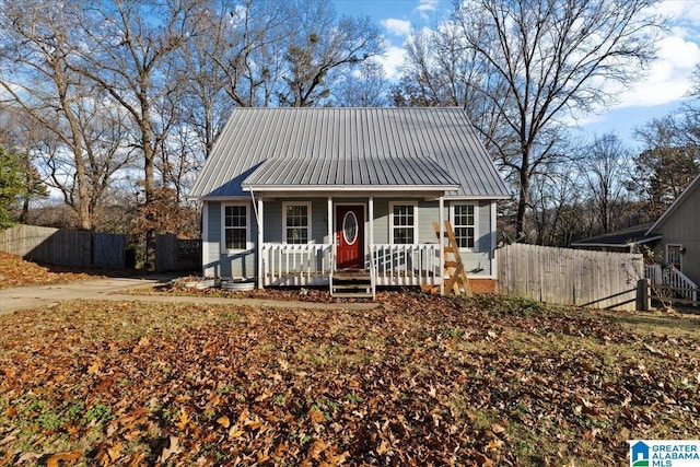 bungalow-style home with fence, covered porch, and metal roof