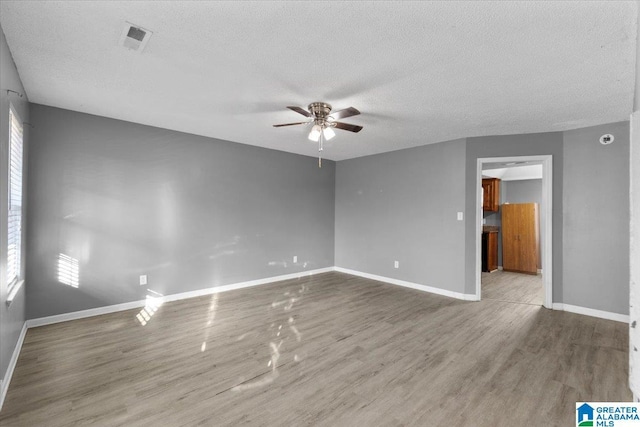 empty room featuring visible vents, ceiling fan, baseboards, wood finished floors, and a textured ceiling