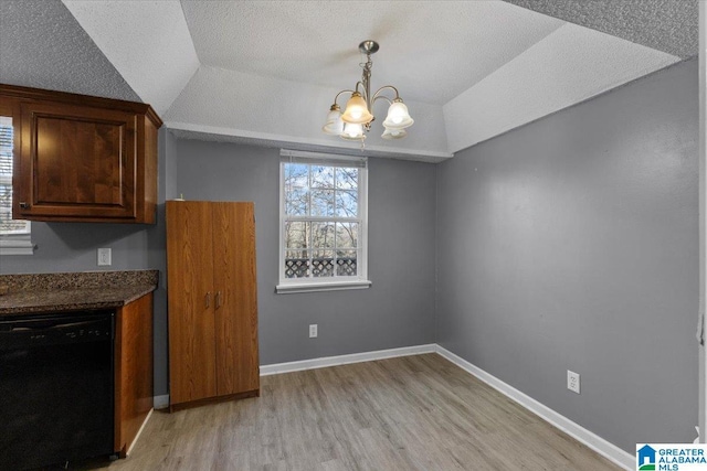 unfurnished dining area with lofted ceiling, light hardwood / wood-style flooring, a textured ceiling, and an inviting chandelier