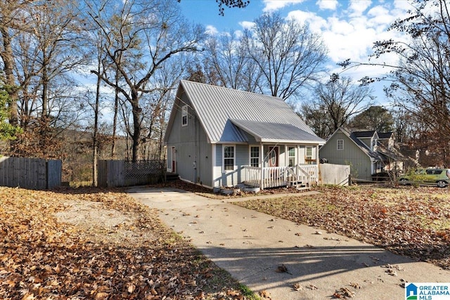 view of front of house featuring metal roof, covered porch, and fence