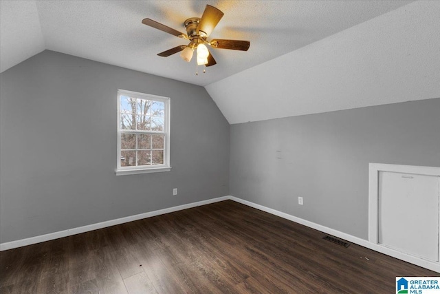 additional living space with a textured ceiling, lofted ceiling, and dark wood-type flooring