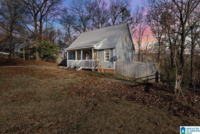 view of front of property featuring fence, covered porch, and metal roof