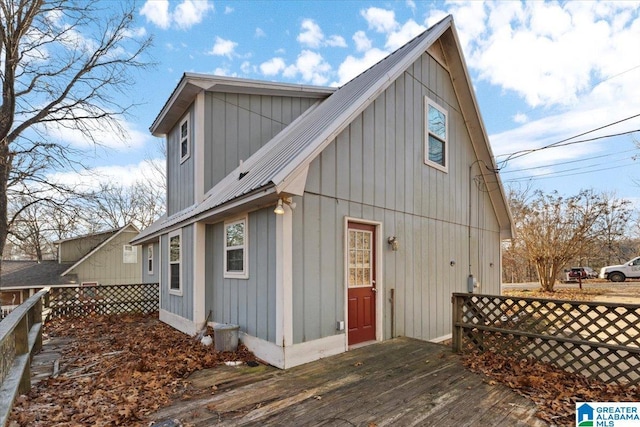 back of house featuring a wooden deck, fence, board and batten siding, and metal roof