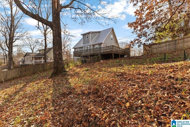 back of house with a wooden deck, metal roof, and fence