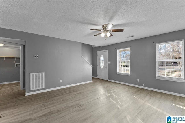 foyer entrance with hardwood / wood-style floors, ceiling fan, and a textured ceiling